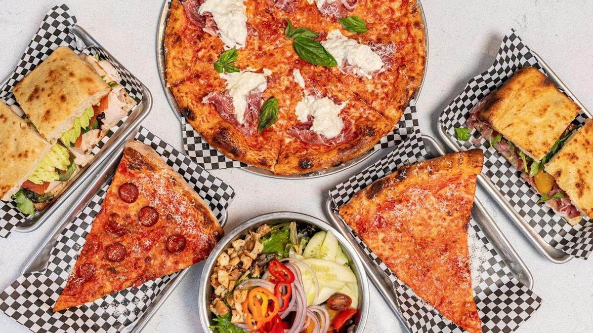 Overhead spread of a Dolce Vita pie, slices, sandwiches and a salad